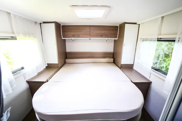 Dormitorio con cama matrimonial y armarios con dos ventanas de la autocaravana Bluecamp Ocean 525